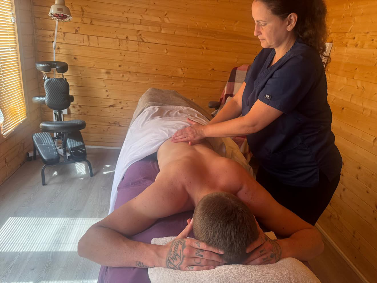 Close-up of Diane massaging a client's back in the wood-lined cabin