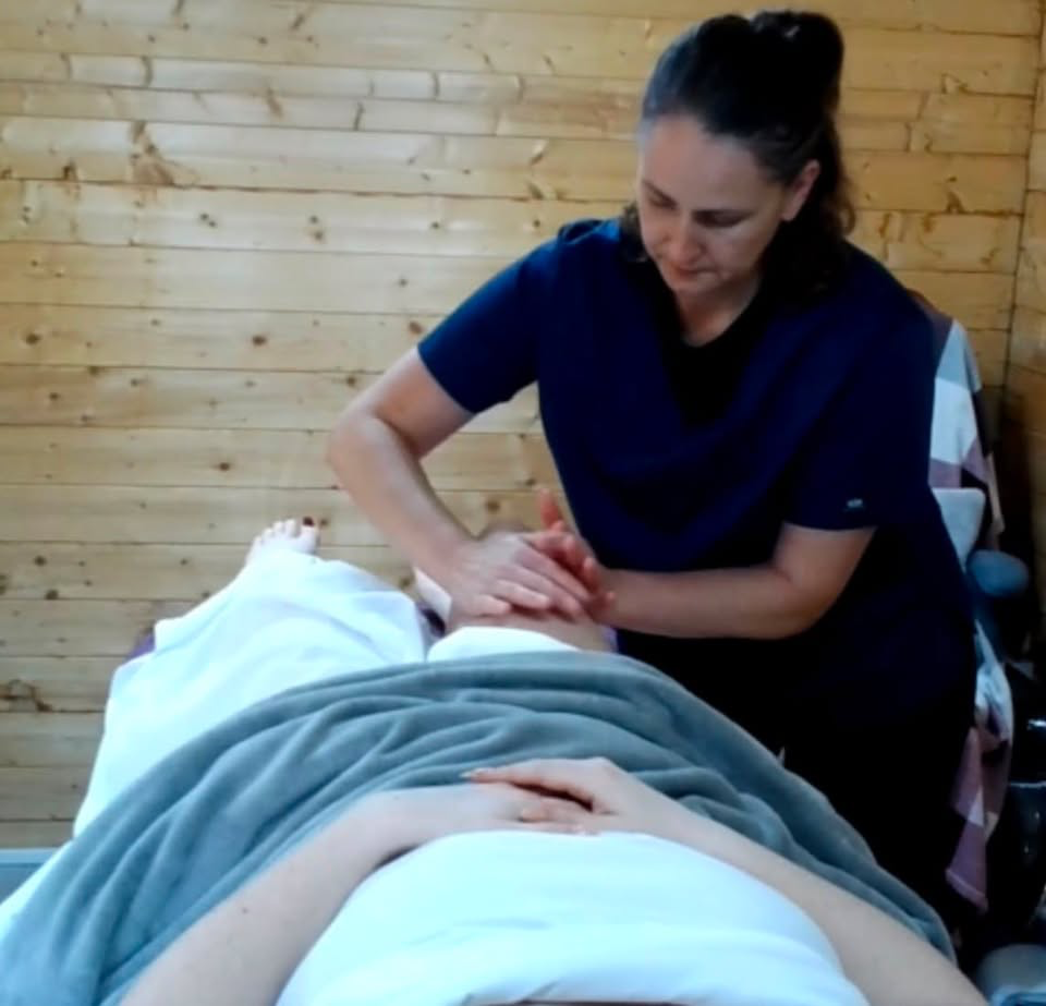 Diane in navy uniform performing a massage in her wood-panelled cabin